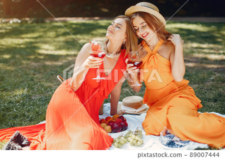 Beautiful girl in a red dress. Women sitting in a summer park. Beautiful girl in a red dress. Women sitting in a summer park. 89007444