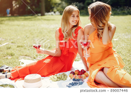 Beautiful girl in a red dress. Women sitting in a summer park. Beautiful girl in a red dress. Women sitting in a summer park. 89007446