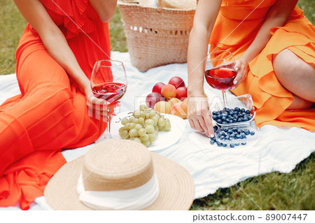 Beautiful girl in a red dress. Women sitting in a summer park. 89007447