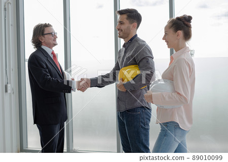 shake hands. Team of male and female engineers and architects, working team, meeting, discussing construction and drawing construction plans, printing, writing on-site construction sites shake hands. Team of male and female engineers and architects, working team, meeting, discussing construction and drawing construction plans, printing, writing on-site construction sites 89010099