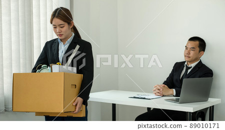 A woman office worker is unhappy with being fired from a company packing things into cardboard boxes. The Young woman was stressed and disappointed by being fired. concept of layoffs and unemployment A woman office worker is unhappy with being fired from a company packing things into cardboard boxes. The Young woman was stressed and disappointed by being fired. concept of layoffs and unemployment 89010171