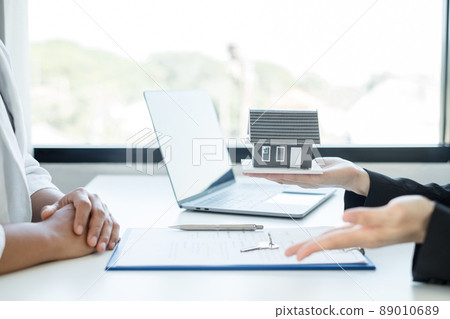 A real estate agent with a House model is talking to clients about buying home insurance. Home insurance concept 89010689