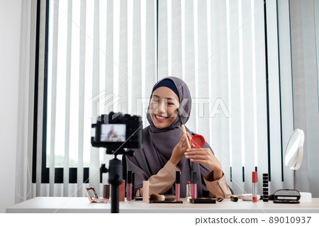 Muslim women making video beauty vlogger bloggers doing a cosmetic makeup tutorial vlog with brushes looking camera Save clips and share them on social media live via the internet Online Muslim women making video beauty vlogger bloggers doing a cosmetic makeup tutorial vlog with brushes looking camera Save clips and share them on social media live via the internet Online 89010937