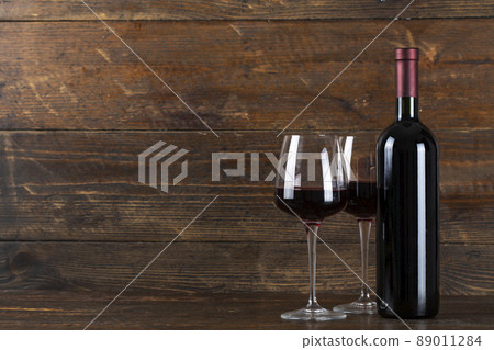 Wine bottle and two glasses on a wooden background. 89011284
