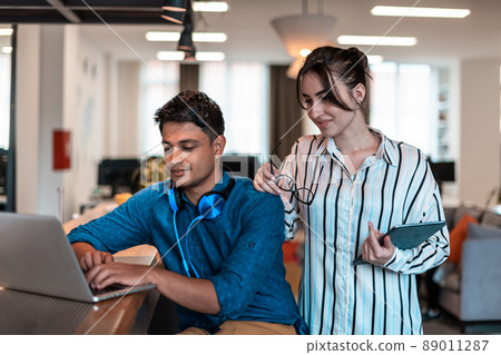 Multiethnic business people man with a female colleague working together on tablet and laptop computer in relaxation area of modern startup office Multiethnic business people man with a female colleague working together on tablet and laptop computer in relaxation area of modern startup office 89011287