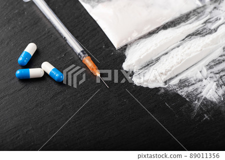 Cocaine or other illegal drugs, white powder, money, pills, syringe on black background. Cocaine or other illegal drugs, white powder, money, pills, syringe on black background. 89011356