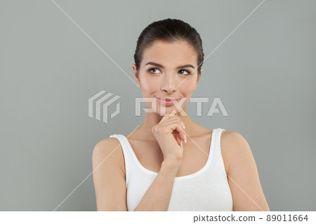 Beautiful young pretty thinking thoughtful woman posing on grey background. 89011664