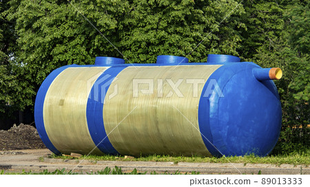 a huge blue container for collecting sewage waste lies on the grass 89013333