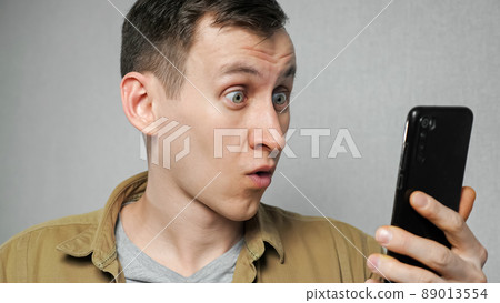 Man removes glasses after reading news on mobile phone Man removes glasses after reading news on mobile phone 89013554