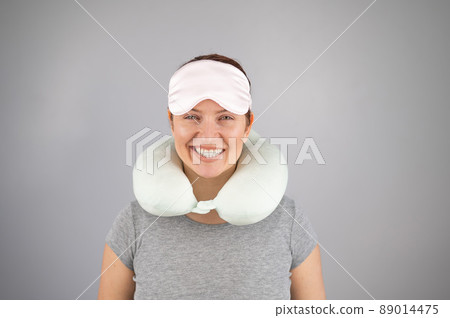 Smiling caucasian woman with travel pillow and sleeping mask isolated on white background. Smiling caucasian woman with travel pillow and sleeping mask isolated on white background. 89014475