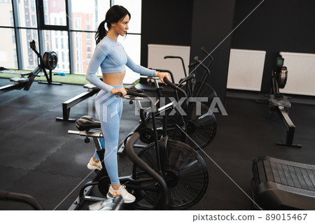 Sportswoman training on exercise bike in gym 89015467
