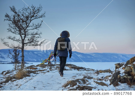 Young man standing in winter frozen nature and watching calm winter misty sunset 89017768