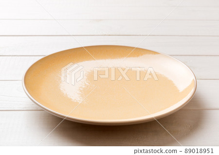 Perspective view of empty orange plate on wooden background. Empty space for your design Perspective view of empty orange plate on wooden background. Empty space for your design 89018951