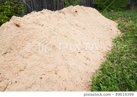 Sawdust stacked in a slide against the background of the lawn. The background is made of natural sawdust. Recycling of woodworking waste. High quality photo 89019399