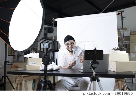 Asian man blogger or vlogger looking at camera reviewing product 89019690