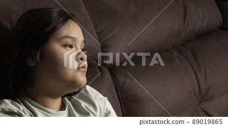 Chubby asian teen girl at home, sitting on the sofa. sad news 89019865