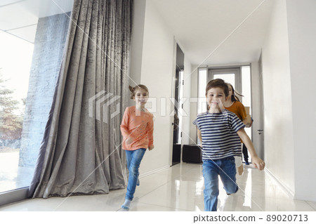 Happy family running in hall. Funny kids jumping with carton box, parents laughing, Happy family running in hall. Funny kids jumping with carton box, parents laughing, 89020713