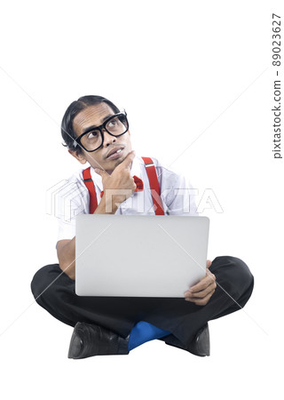 Asian nerd with ugly face sitting while using a laptop and thinking something 89023627