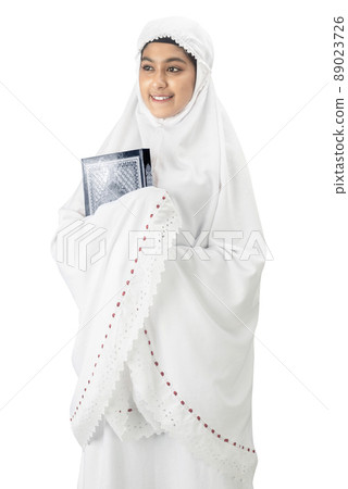 Asian Muslim woman in a veil standing and holding the Quran Asian Muslim woman in a veil standing and holding the Quran 89023726