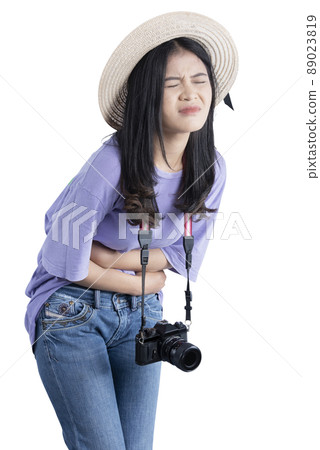 Asian woman with hat and camera having stomach pain while traveling Asian woman with hat and camera having stomach pain while traveling 89023819