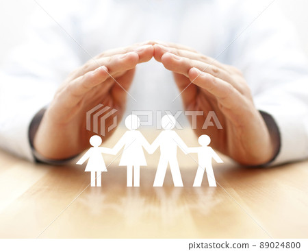 Family insurance concept with paper family cutout covered by hands 89024800