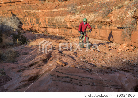 riding fat bike on slickrock at canyon bottom riding fat bike on slickrock at canyon bottom 89024809
