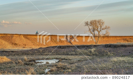 lonely cyclist riding fat mountain bike on a cliff 89024817