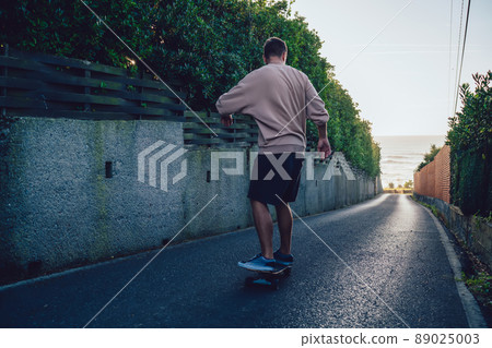 Faceless young athletic man balancing on longboard 89025003