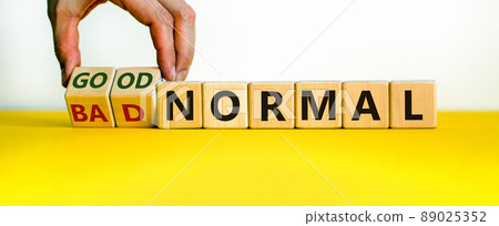 Good vs bad normal symbol. Businessman turns wooden cubes and changes words 'bad normal' to 'good normal'. Beautiful yellow table, white background, copy space. Business and good normal concept. 89025352