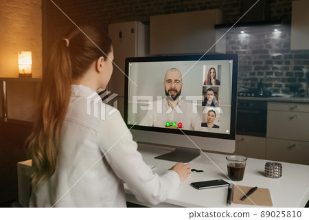 Back view of woman talking to her colleagues in a video conference on computer. 89025810