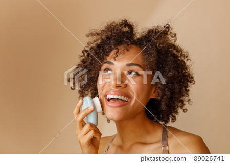 Multiethnic woman toothy smiling on beige background of studio 89026741