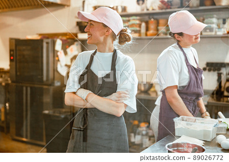 Cheerful woman with colleague stand at table with fresh food products Cheerful woman with colleague stand at table with fresh food products 89026772