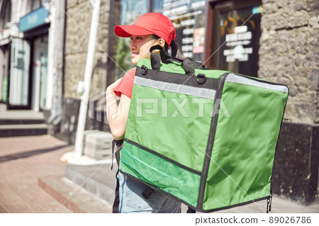 Asian delivery woman walking down urban street 89026786