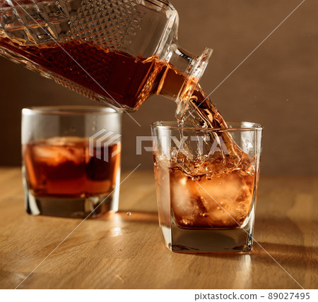 Whiskey is poured into a dammed glass with ice. 89027495