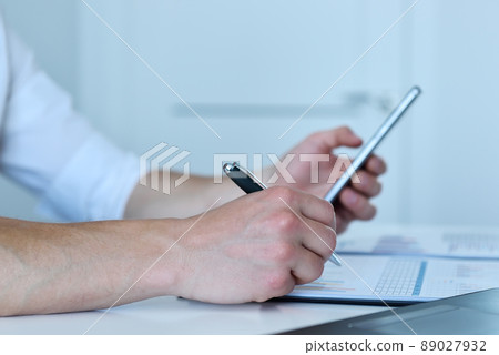 Manager checks the statistics on smart phone. 89027932