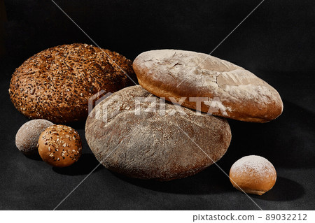 Assortment of tasty baked round bread and buns with sesame and sunflower seeds, sprinkled with flour. Black background, copy space. Close-up Assortment of tasty baked round bread and buns with sesame and sunflower seeds, sprinkled with flour. Black background, copy space. Close-up 89032212