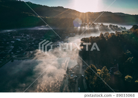 Aerial view of Sunrise with fog over Ban Rak thai, chinese village near a lake in Mae Hong Son Aerial view of Sunrise with fog over Ban Rak thai, chinese village near a lake in Mae Hong Son 89033068