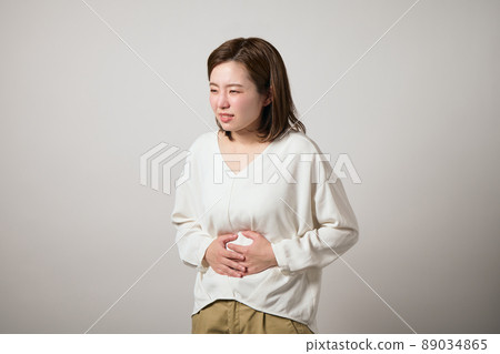 A young woman who has a stomachache and can hold her hands A young woman who has a stomachache and can hold her hands 89034865