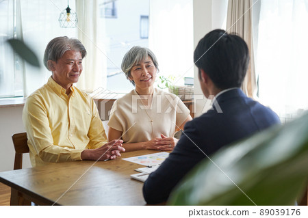 An elderly couple having a conversation at home with a sales man 89039176