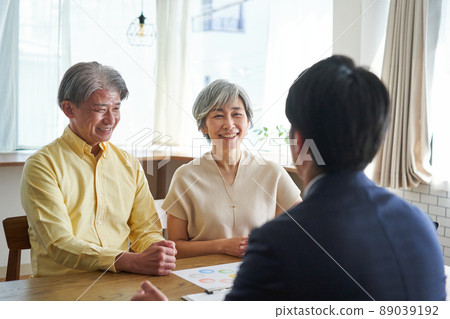 An elderly couple having a conversation at home with a sales man 89039192