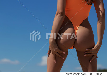 Graceful woman in orange swimsuit relaxing on beach 89040356