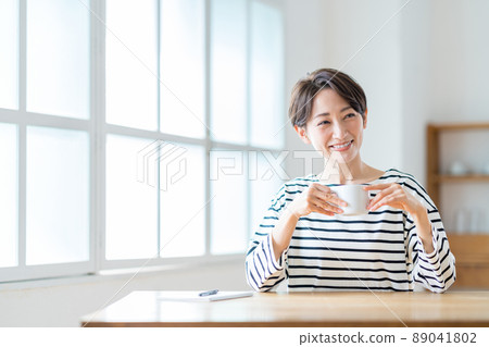 客廳裡喝著咖啡的中年婦女。 客廳裡喝著咖啡的中年婦女。 89041802