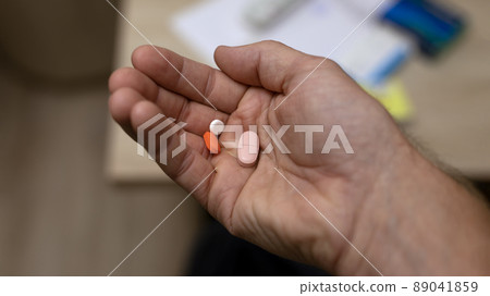 man's hand holding several pills in his hand man's hand holding several pills in his hand 89041859
