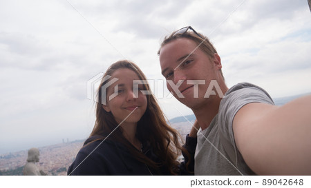 A young couple taking a selfie on observation deck. Barcelona city aerial view. City overview. A young couple taking a selfie on observation deck. Barcelona city aerial view. City overview. 89042648