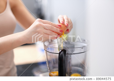 Woman adds eggs to blender for dough Woman adds eggs to blender for dough 89044575