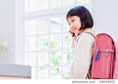 Elementary school student carrying a school bag waving 89048903