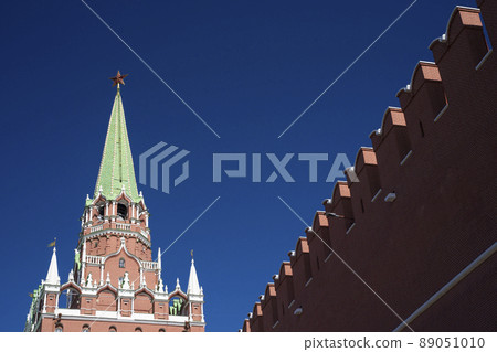 View of the Trinity tower of the Moscow Kremlin with a fortress wall on a Sunny spring day. World tourism, sights of Moscow. High quality photo 89051010