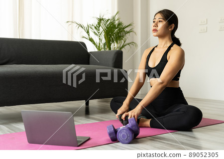 Beautiful young asian woman practicing yoga watching videos on laptop at home - Fitness, workout concept Beautiful young asian woman practicing yoga watching videos on laptop at home - Fitness, workout concept 89052305