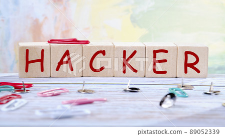 The inscription Hacker on wooden cubes on a table with scattered paper clips The inscription Hacker on wooden cubes on a table with scattered paper clips 89052339
