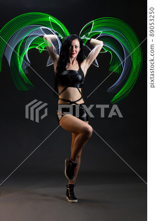 Light trail. Shooting with combined lighting. Young professional athlete plays with lighting equipment on a black background in mixed light. Working out in motion, action. Strength and energy. 89053250